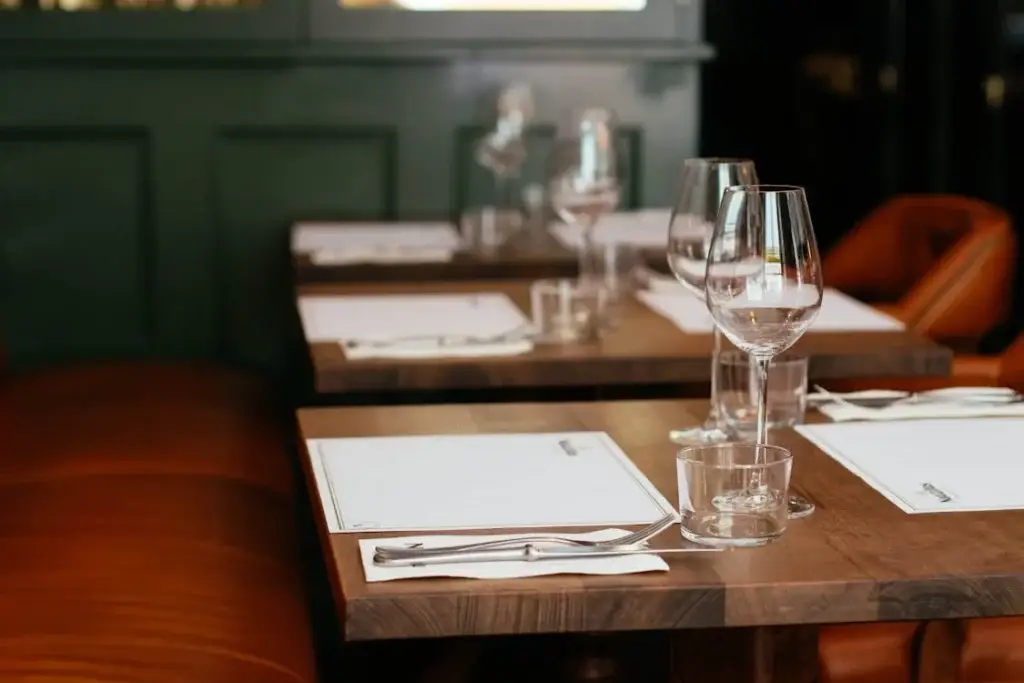 The inside of a London restaurant with dining tables and chairs and shining wine glasses.