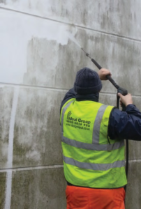 technican removing algae from side of building