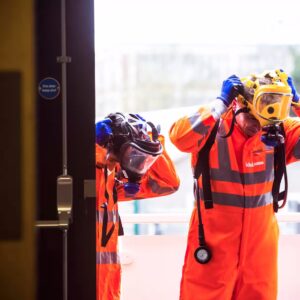 Two technicians in breathing equipment entiring a property.