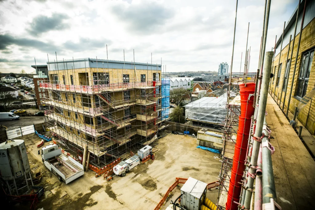 An areal view of the development site with multiple four story building structures with scaffolding on the exterior walls.