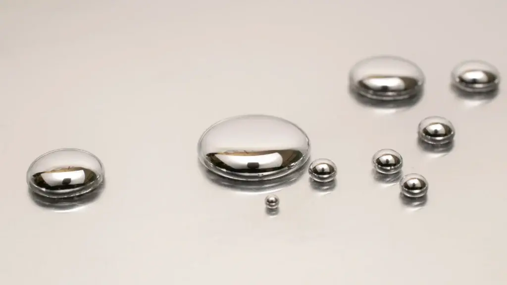 Balls of mercury on a grey surface after a broken thermometer caused the spill.