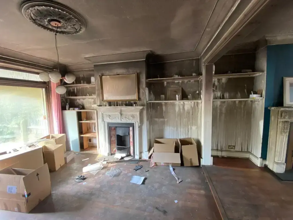 A fire damaged sitting room with blacked soot stained walls and ceiling.