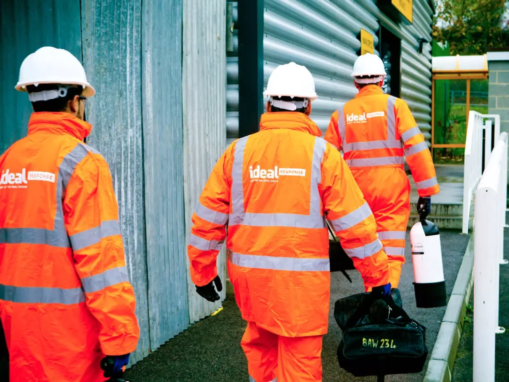 Three specialist cleaning technicians in high-vis clothing carrying cleaning equipment.