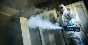 A technician using a fog machine during a smoke odour removal service in a domestic property.