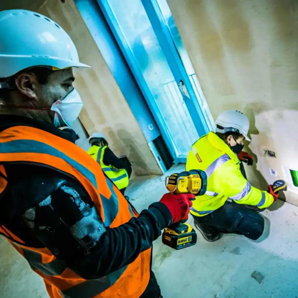 Technician shining a light on the wall off a construction project for another technician to take a moisture reading.
