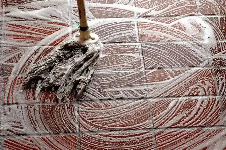 Soapy mop being used on a tiled floor.