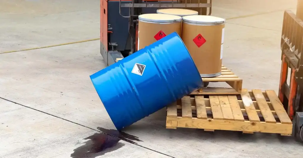 Chemical barrel tipped over spilling contents in a commercial yard.