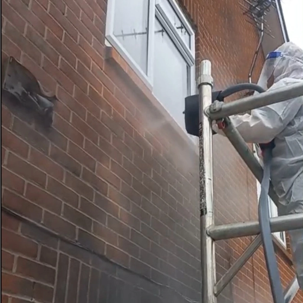 Technician cleaning exterior of house