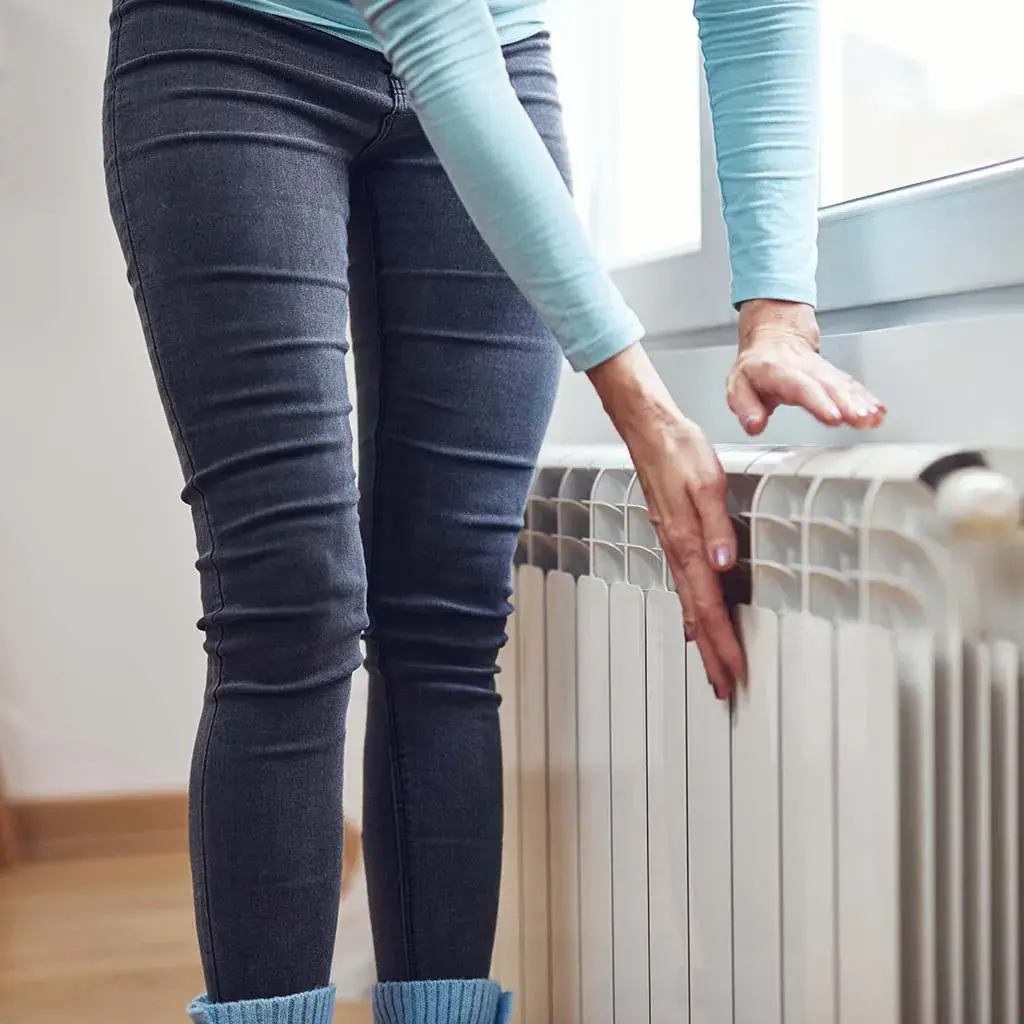 Woman turning on a radiator.